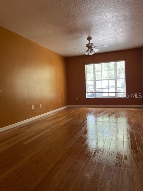 An empty room features orange walls, a ceiling fan, and polished wood flooring — 8434 QUARTER HORSE DRIVE, RIVERVIEW, FL