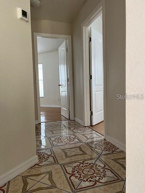 A hallway with patterned tile flooring leads to two open doorways showing interior rooms — 8434 QUARTER HORSE DRIVE, RIVERVIEW, FL