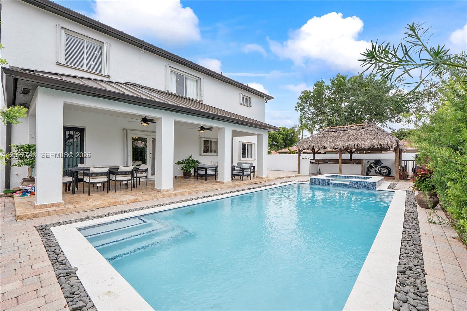 A two-story house features a covered patio, a swimming pool, and a thatched-roof tiki hut — 16732 NW 89th Pl, Miami Lakes FL 33018, MIAMI LAKES, FL