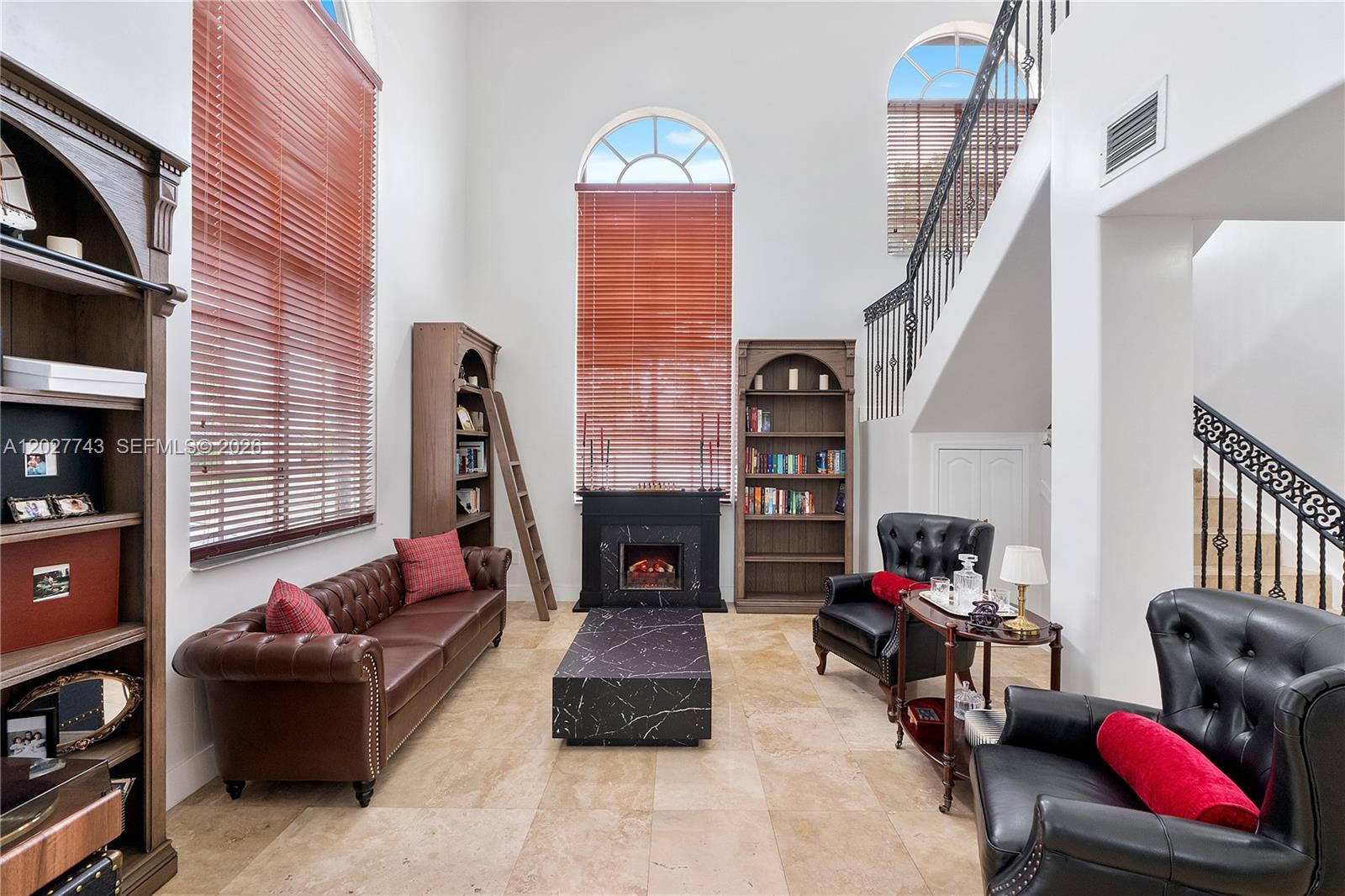 A living room features a fireplace, leather furniture, tall bookshelves, and a staircase — 16732 NW 89th Pl, Miami Lakes FL 33018, MIAMI LAKES, FL