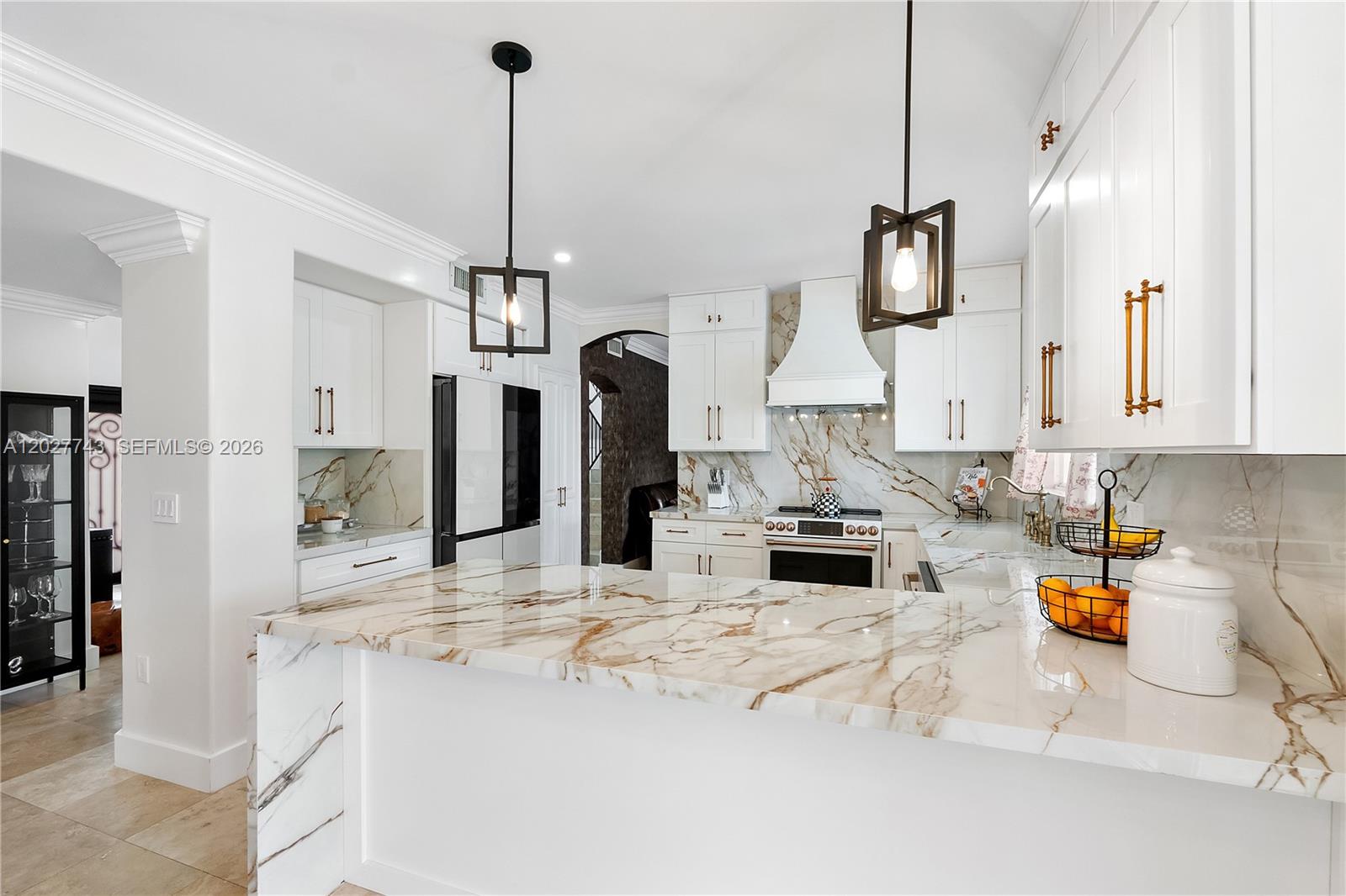 A modern kitchen features white cabinets, gold hardware, and marble countertops with a waterfall edge — 16732 NW 89th Pl, Miami Lakes FL 33018, MIAMI LAKES, FL