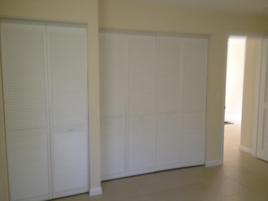 A room features two sets of white louvered closet doors against light-colored walls — 203 SE 4th Avenue, Boynton Beach FL 33435, BOYNTON BEACH, FL