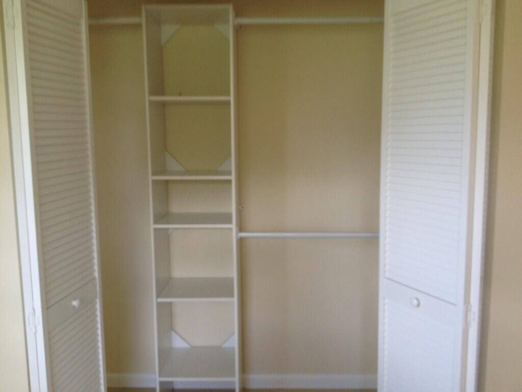 A closet with white louvered doors, a central shelving unit, and two hanging rods — 203 SE 4th Avenue, Boynton Beach FL 33435, BOYNTON BEACH, FL