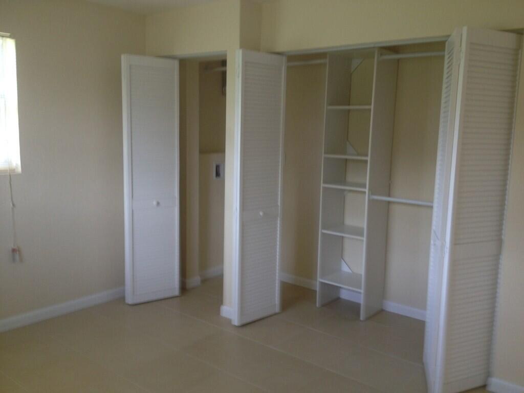 A room with light-colored tile flooring, beige walls, and two white louvered-door closets — 203 SE 4th Avenue, Boynton Beach FL 33435, BOYNTON BEACH, FL