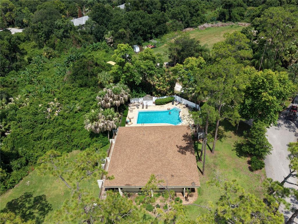 An aerial view shows a house with a brown roof and a backyard swimming pool — 200 EL CAMINO DRIVE UNIT 306, WINTER HAVEN, FL