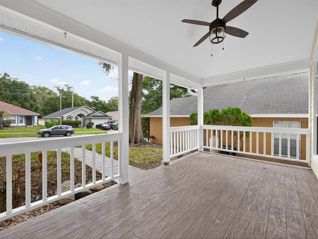 A covered porch with a ceiling fan, white railings, and wood-look flooring overlooks a neighborhood — 1008 ROYAL OAKS DRIVE, APOPKA, FL