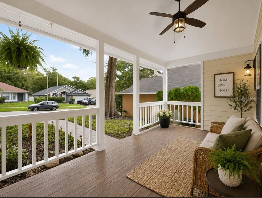 A covered front porch features wood-look flooring, white railings, a ceiling fan, and wicker furniture — 1008 ROYAL OAKS DRIVE, APOPKA, FL