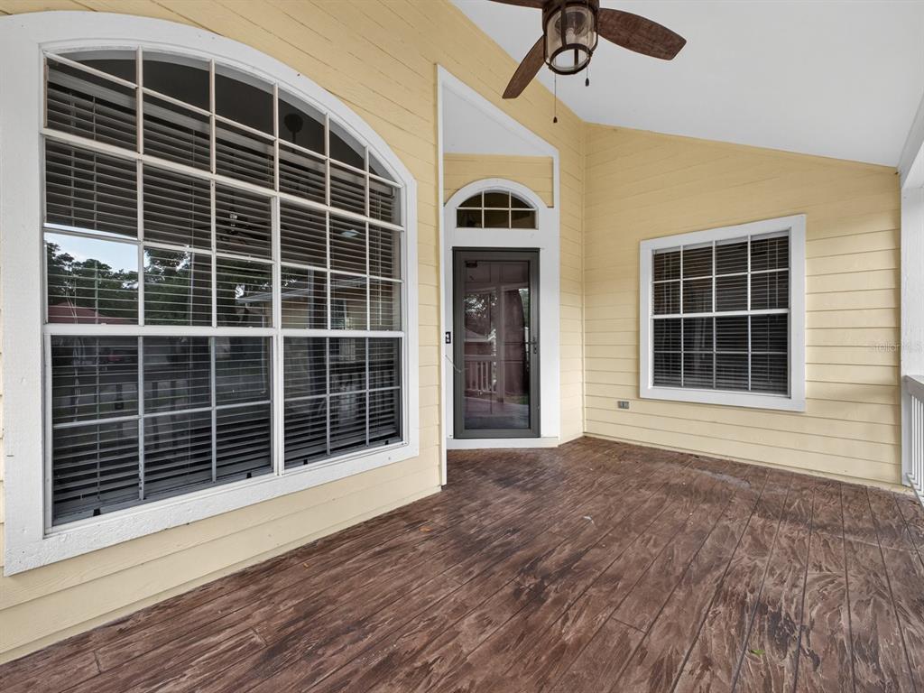 A covered porch with yellow siding, a ceiling fan, and a dark wood-look floor — 1008 ROYAL OAKS DRIVE, APOPKA, FL