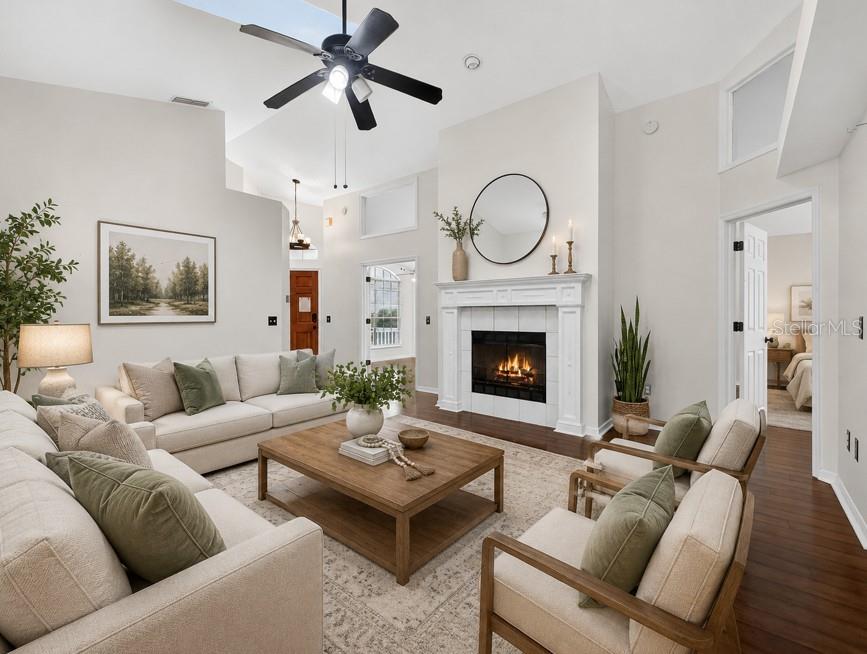 A living room features a fireplace, vaulted ceilings, a ceiling fan, and neutral furniture — 1008 ROYAL OAKS DRIVE, APOPKA, FL