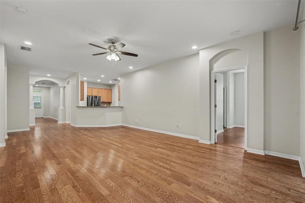 An open-concept living area features hardwood floors, a ceiling fan, and a kitchen pass-through window — 15536 GANNETGLADE LANE, LITHIA, FL