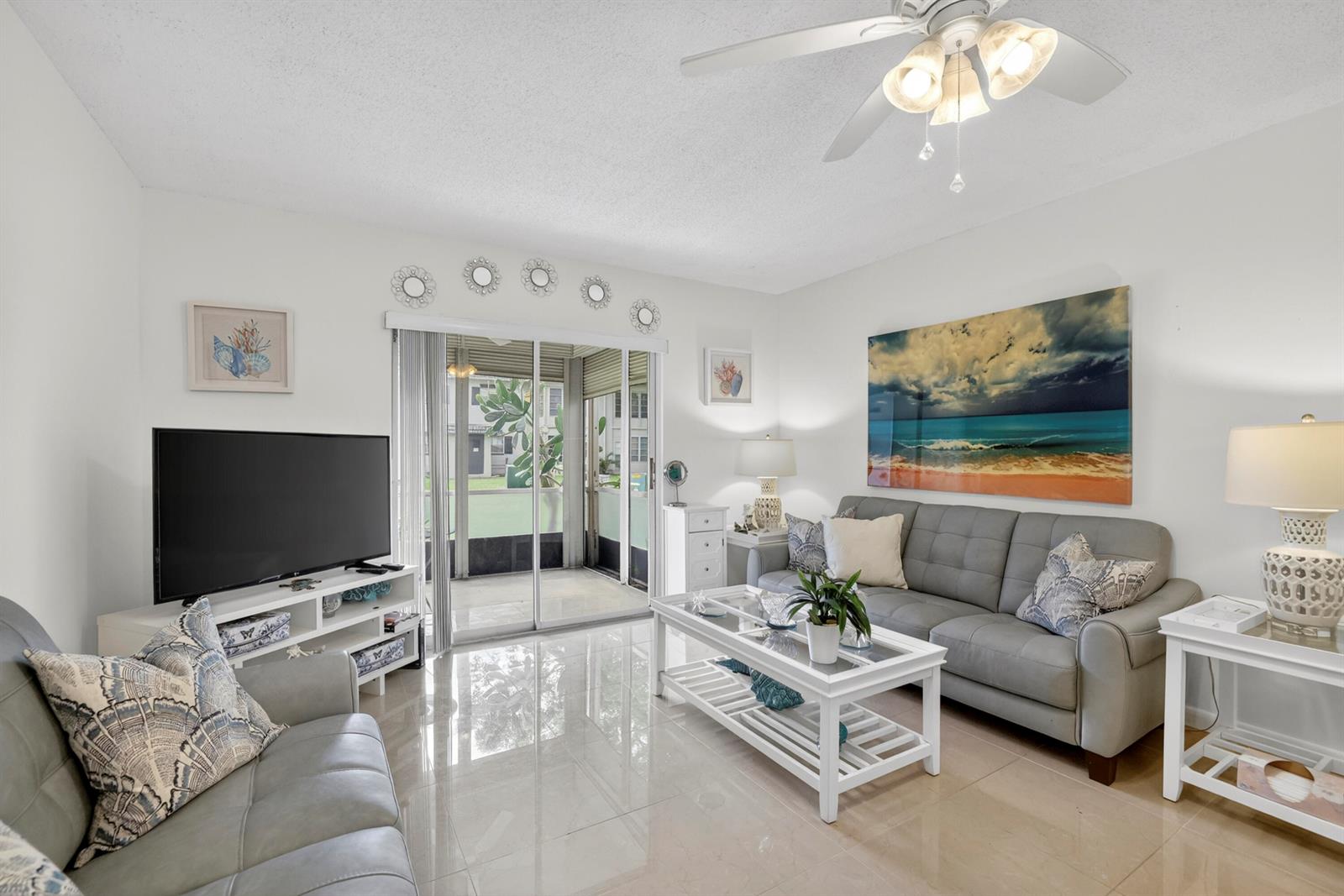 A living room features light tile floors, a grey sofa, a coffee table, and a patio — 5681 SW 2nd Court # 106, Margate FL 33068, MARGATE, FL