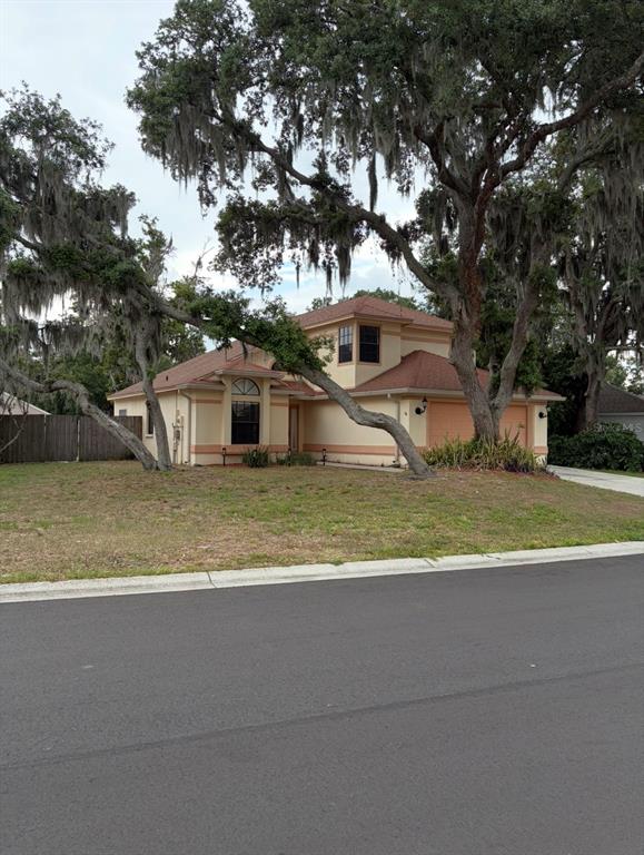 A two-story tan house with a red roof stands behind large trees with Spanish moss — 4308 KIPLING AVENUE, PLANT CITY, FL