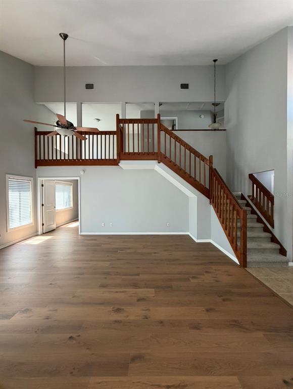 A living room features wood flooring, a wooden staircase, and a lofted balcony area — 4308 KIPLING AVENUE, PLANT CITY, FL