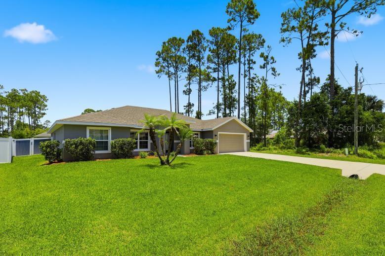 A single-story house with a gray exterior, a concrete driveway, and a large front lawn — 55 BENNETT LANE, PALM COAST, FL
