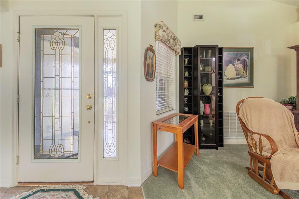 An entryway features a glass-paneled door, a wooden side table, a display cabinet, and carpeting — 112 MONACO DRIVE, DAVENPORT, FL