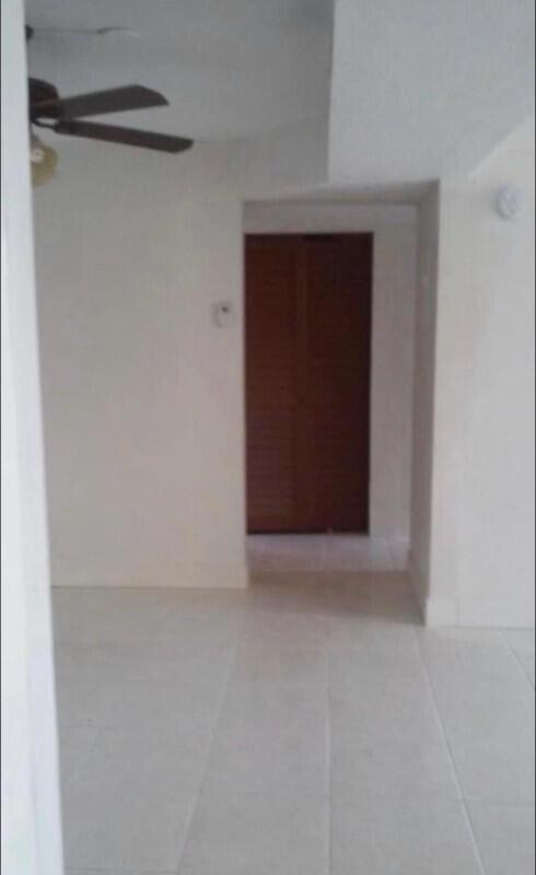 A view of a room with white tile flooring, a ceiling fan, and wooden doors — 3550 Blue Lake Drive # 404, Pompano Beach FL 33064, POMPANO BEACH, FL