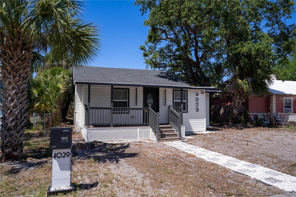 A small, white, single-story house with a front porch sits on a sandy lot — 4029 13TH AVENUE S, ST PETERSBURG, FL