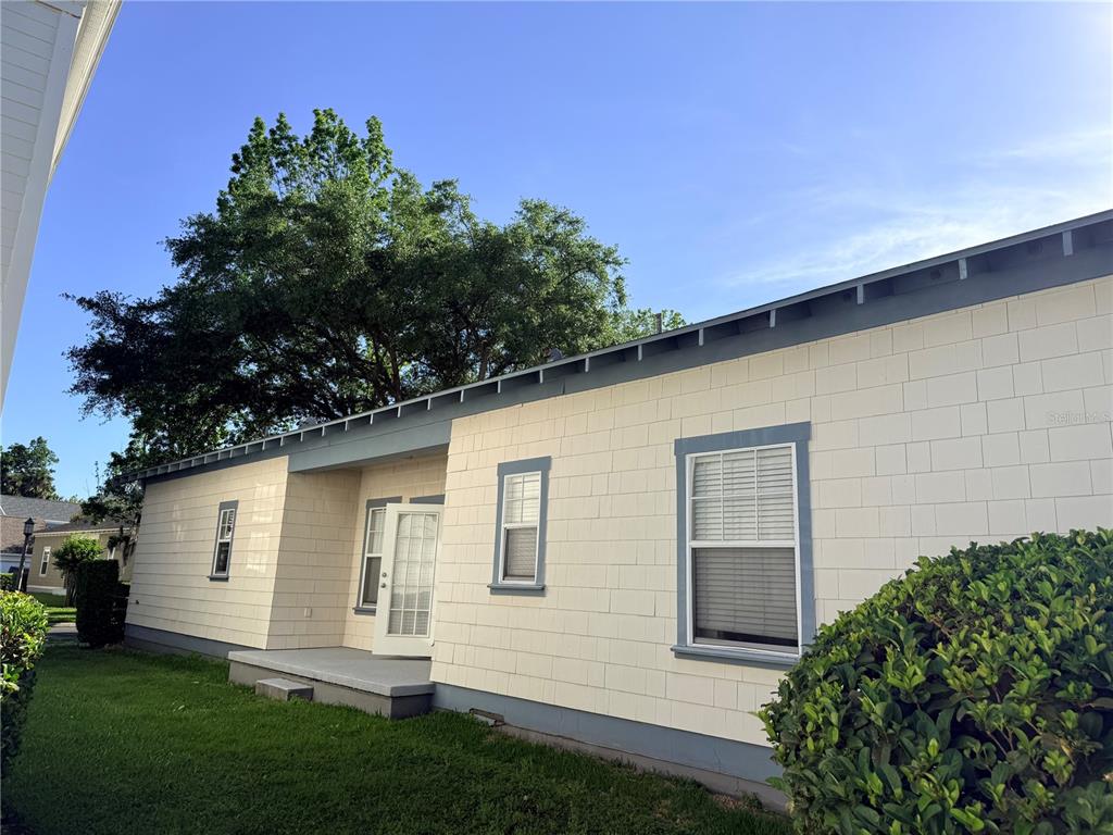 A side view of a light-colored house with a small porch and green lawn — 1110 OAK POND DRIVE, CELEBRATION, FL
