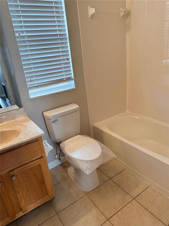 A bathroom features a wooden vanity, a toilet with a bubble-wrapped seat, and a tub — 1110 OAK POND DRIVE, CELEBRATION, FL