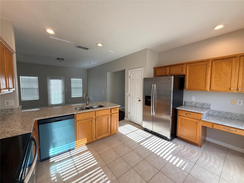 A kitchen features oak cabinets, granite countertops, stainless steel appliances, and tile flooring — 1110 OAK POND DRIVE, CELEBRATION, FL