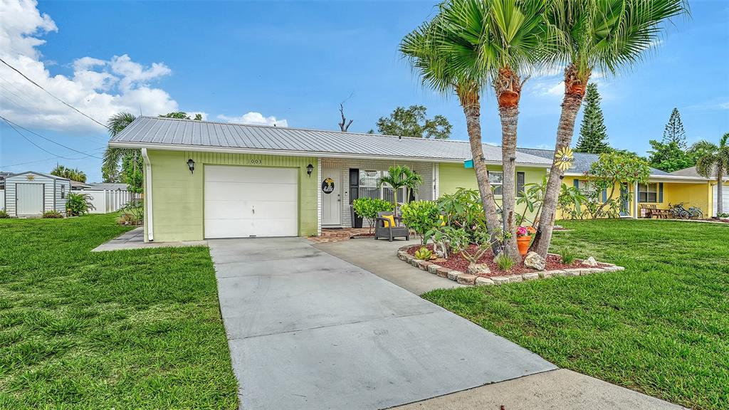 A light green single-story house with a metal roof, garage, and palm trees in front — 1003 21ST AVENUE W, PALMETTO, FL
