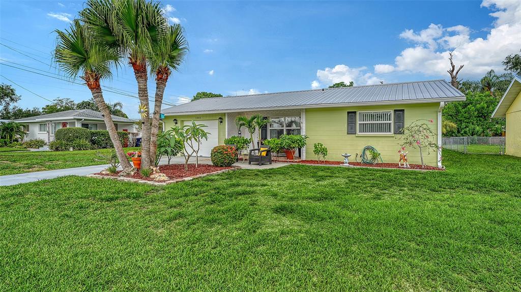 A light green single-story house with a metal roof and palm trees in the yard — 1003 21ST AVENUE W, PALMETTO, FL
