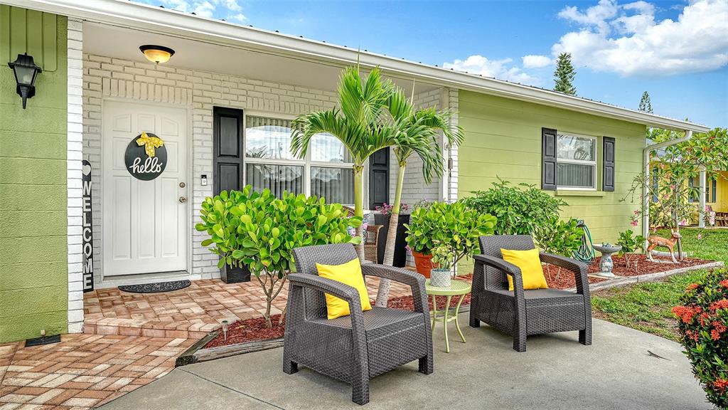 The exterior of a light green house features a brick entryway, two chairs, and landscaping — 1003 21ST AVENUE W, PALMETTO, FL