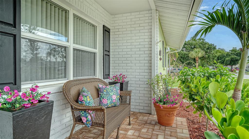 A wicker bench sits on a brick-paved porch in front of a white brick wall — 1003 21ST AVENUE W, PALMETTO, FL