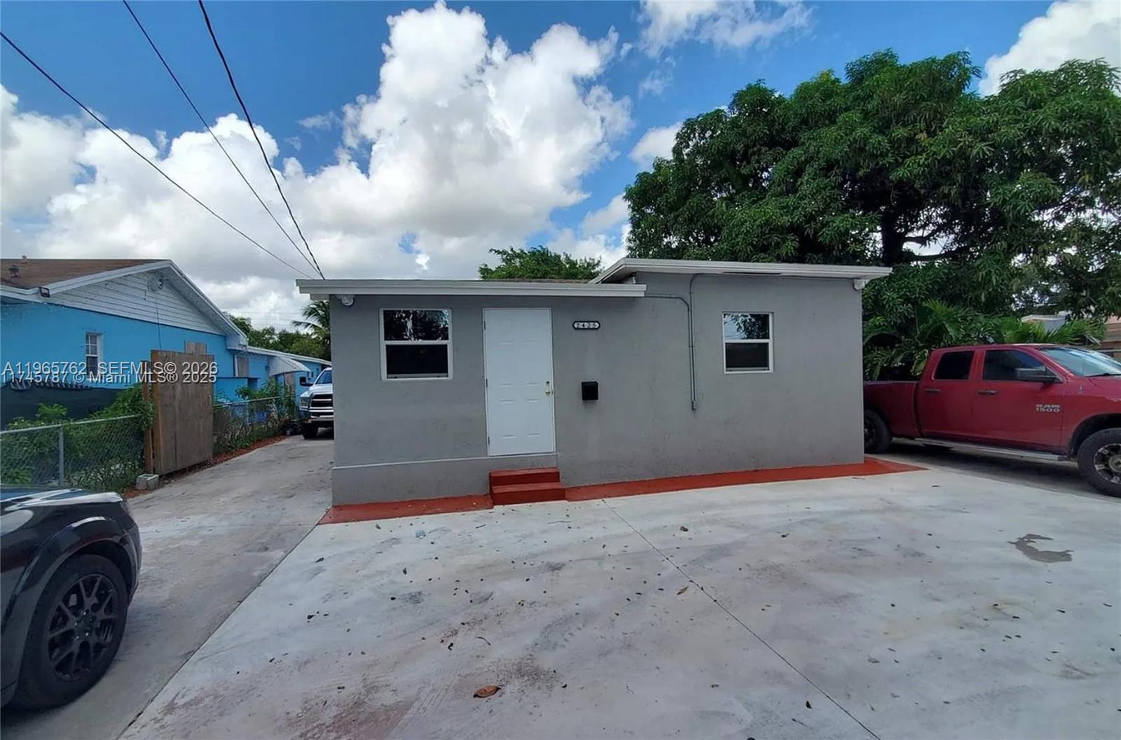A small, gray, single-story house with a white door and a concrete driveway — 2425 NW 28th St, Miami FL 33142, MIAMI, FL