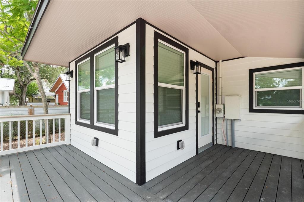 A covered wooden deck features white siding with black trim and several exterior wall lights — 136 N RING AVENUE, TARPON SPRINGS, FL