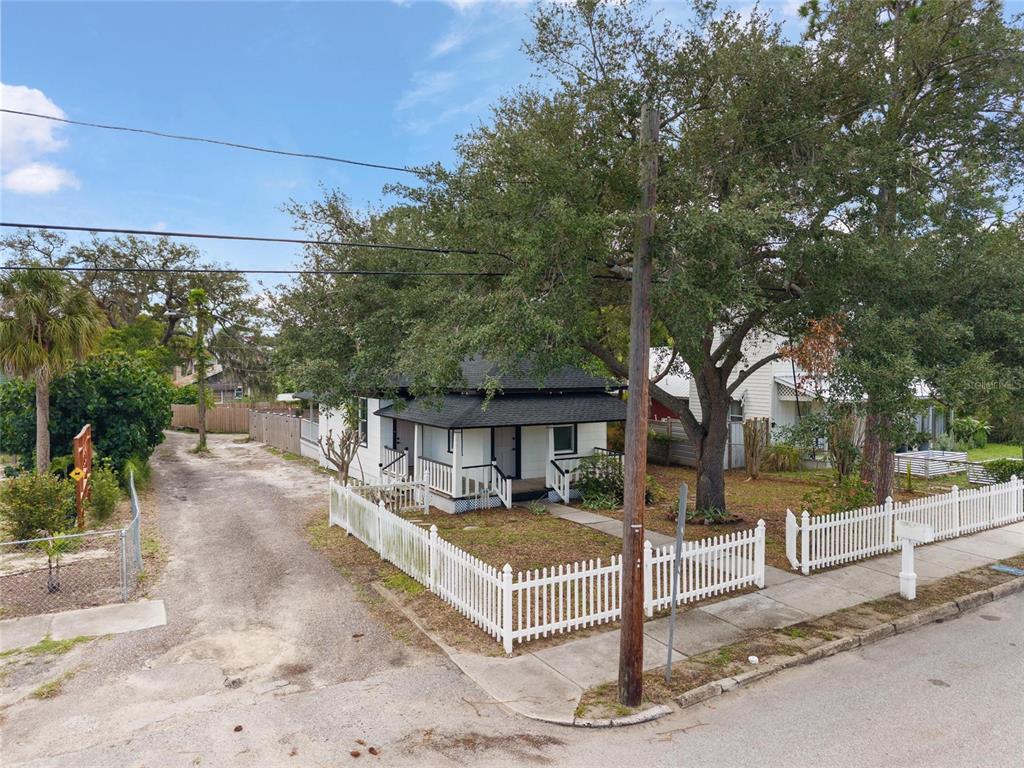 A white house with a black roof and a white picket fence sits on a corner — 136 N RING AVENUE, TARPON SPRINGS, FL
