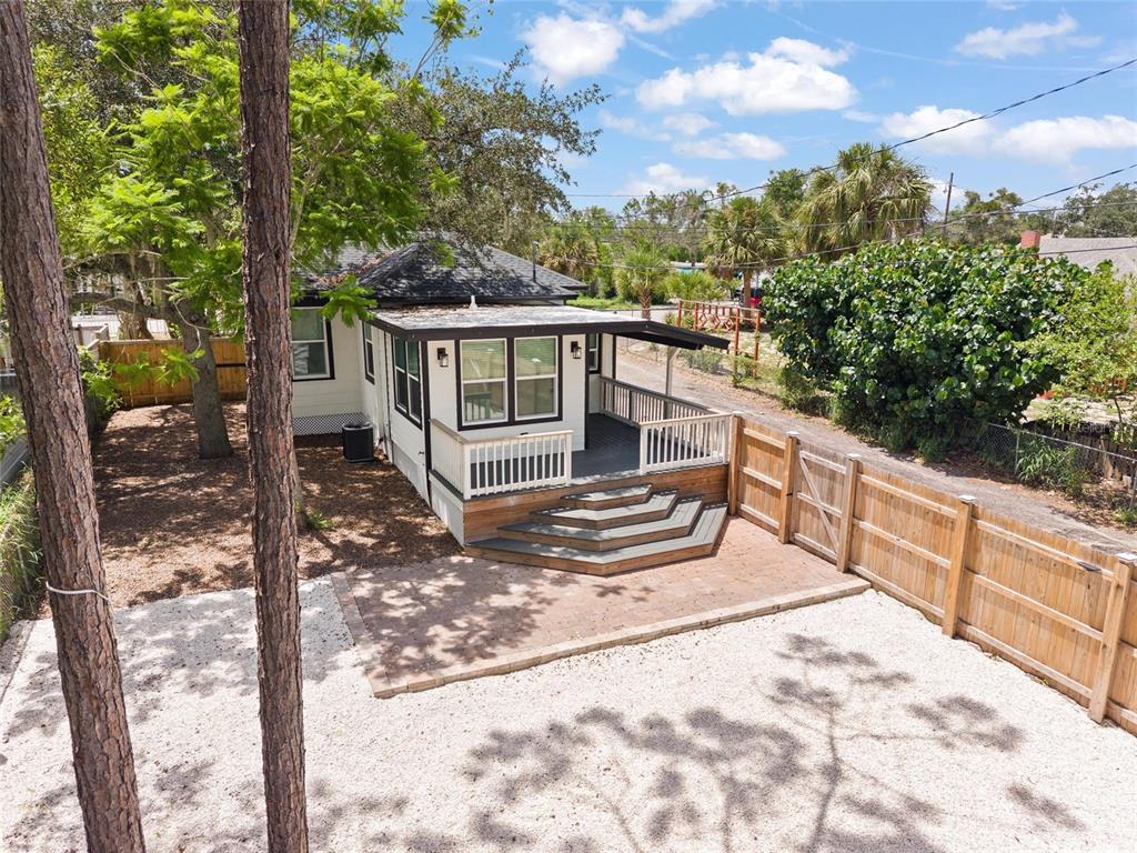 An elevated view of a house exterior featuring a wooden deck, stairs, and gravel yard — 136 N RING AVENUE, TARPON SPRINGS, FL