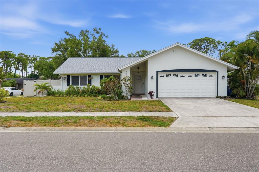 A single-story house with a white exterior, a two-car garage, and a front lawn — 3052 HERON PLACE, CLEARWATER, FL