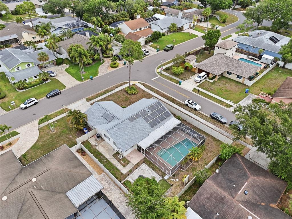 An aerial view shows a residential house with a solar-paneled roof and a screened pool — 3052 HERON PLACE, CLEARWATER, FL
