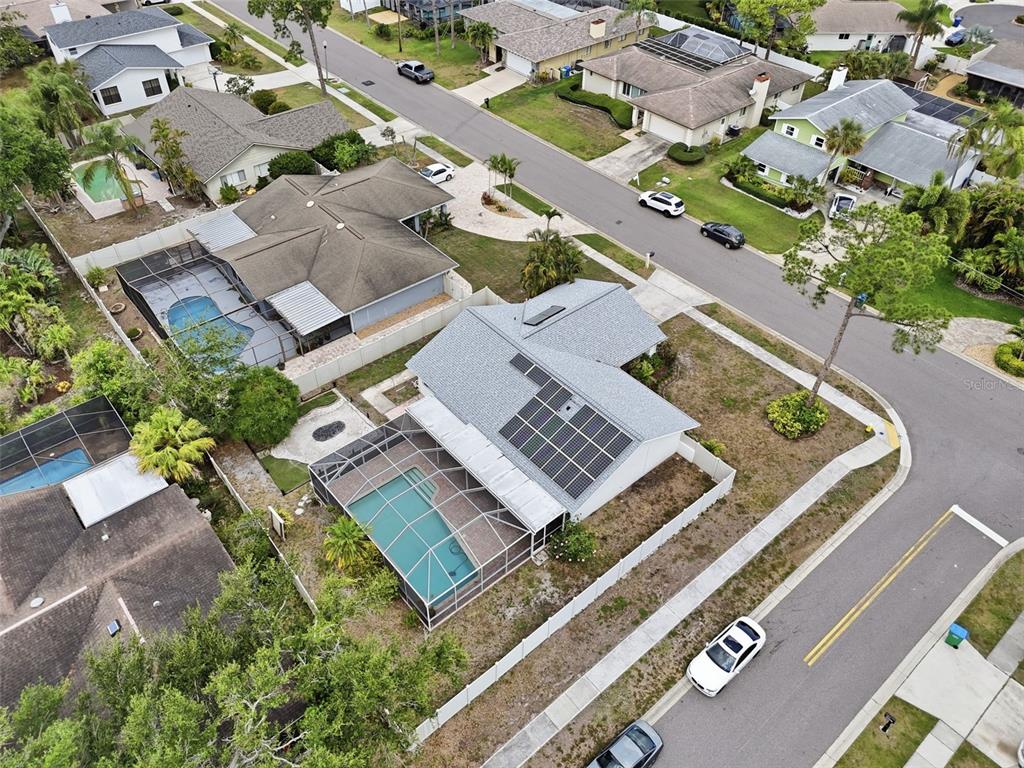 An aerial view shows a suburban neighborhood with houses featuring swimming pools and solar panels — 3052 HERON PLACE, CLEARWATER, FL