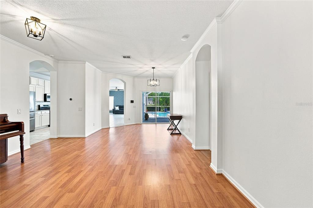 A bright living area features wood-look flooring, white walls, and a view of a pool — 12018 NORTHUMBERLAND DRIVE, TAMPA, FL