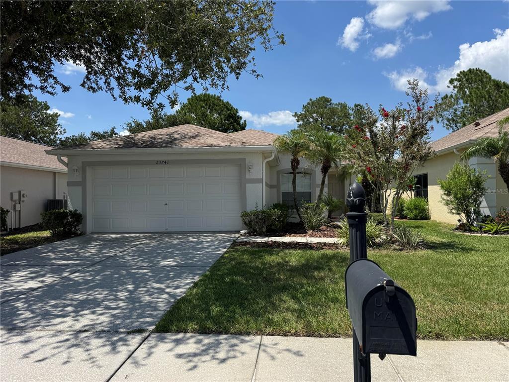 A single-story house with a white garage door, a concrete driveway, and a mailbox — 23741 CORAL RIDGE LANE, LAND O LAKES, FL
