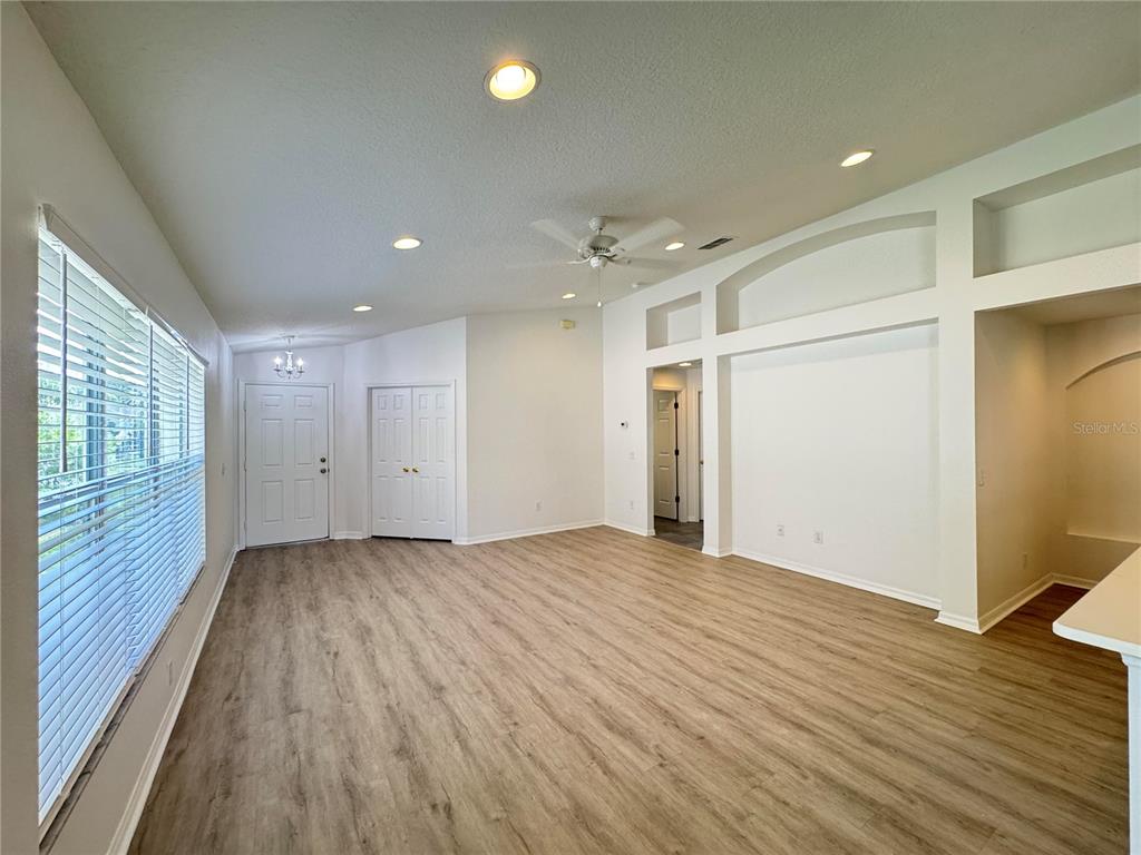 An empty living room features light wood-look flooring, white walls, and a ceiling fan — 23741 CORAL RIDGE LANE, LAND O LAKES, FL