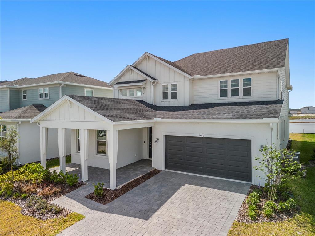A two-story house with a white exterior, a covered front porch, and a dark garage door — 9662 PASSAIC PARKWAY, ORLANDO, FL