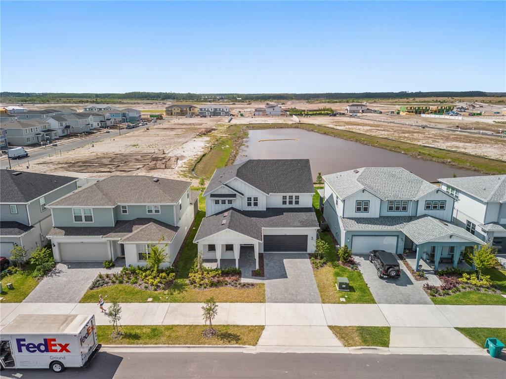 An aerial view shows three suburban houses with paved driveways facing a street and pond — 9662 PASSAIC PARKWAY, ORLANDO, FL