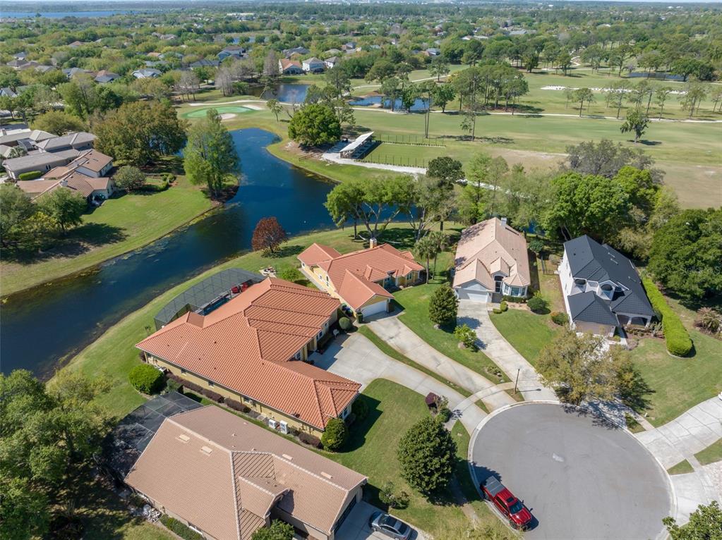 An aerial view shows several suburban houses with tile roofs near a pond and golf course — 14050 FAIRWAY WILLOW LANE, WINTER GARDEN, FL