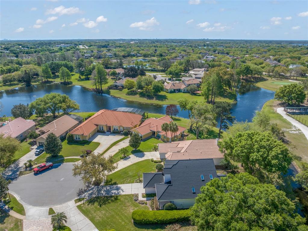 An aerial view shows several suburban houses with tiled roofs situated near a winding lake — 14050 FAIRWAY WILLOW LANE, WINTER GARDEN, FL