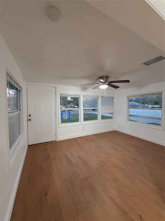 An empty room with light wood-look flooring, white walls, a ceiling fan, and multiple windows — 636 COKE AVENUE, WINTER GARDEN, FL