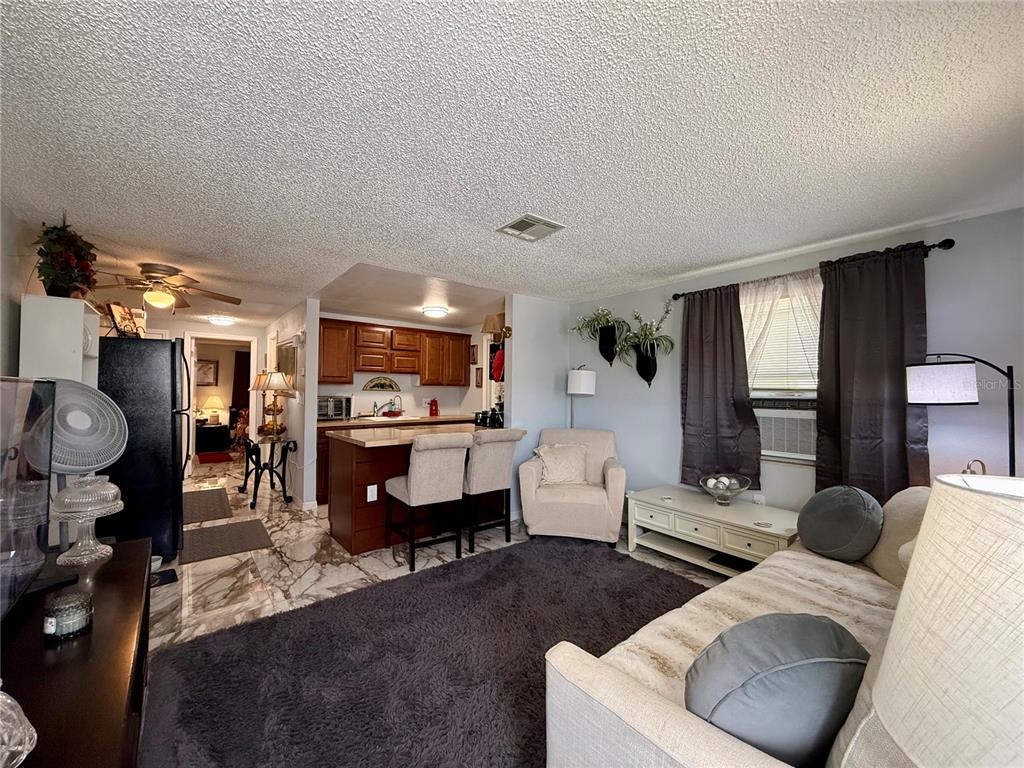 A living room with marble-look tile floors opens to a kitchen with a breakfast bar — 4926 FILNER STREET, NEW PORT RICHEY, FL