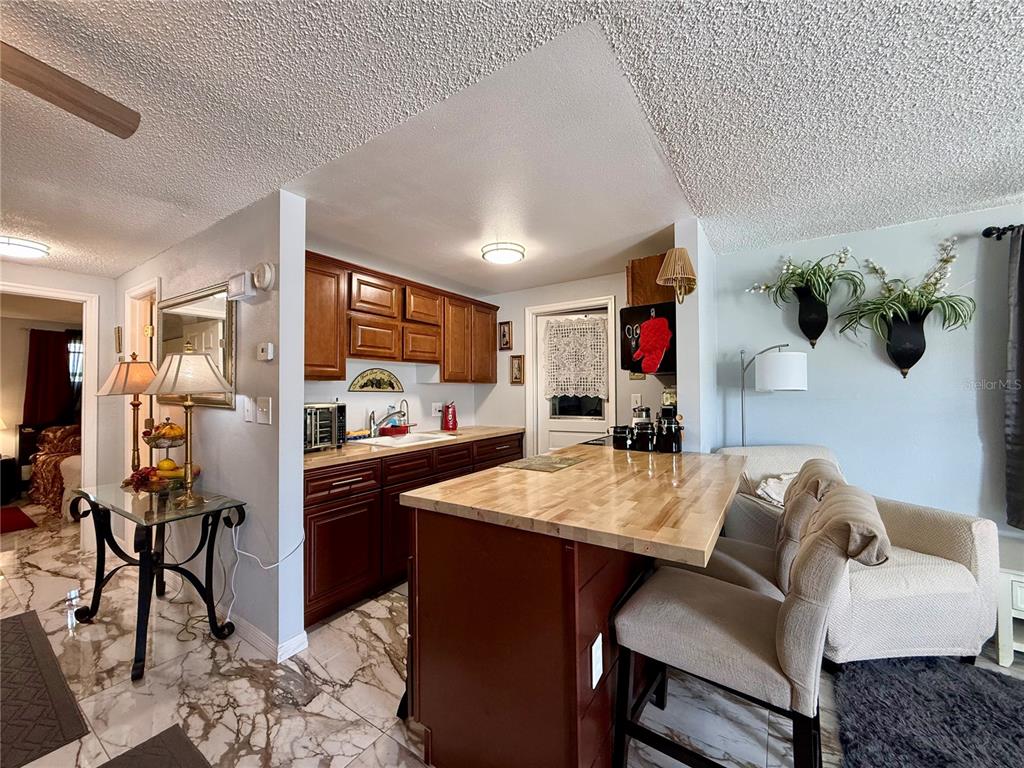 A kitchen with wood cabinets and a butcher block island sits next to a living area — 4926 FILNER STREET, NEW PORT RICHEY, FL