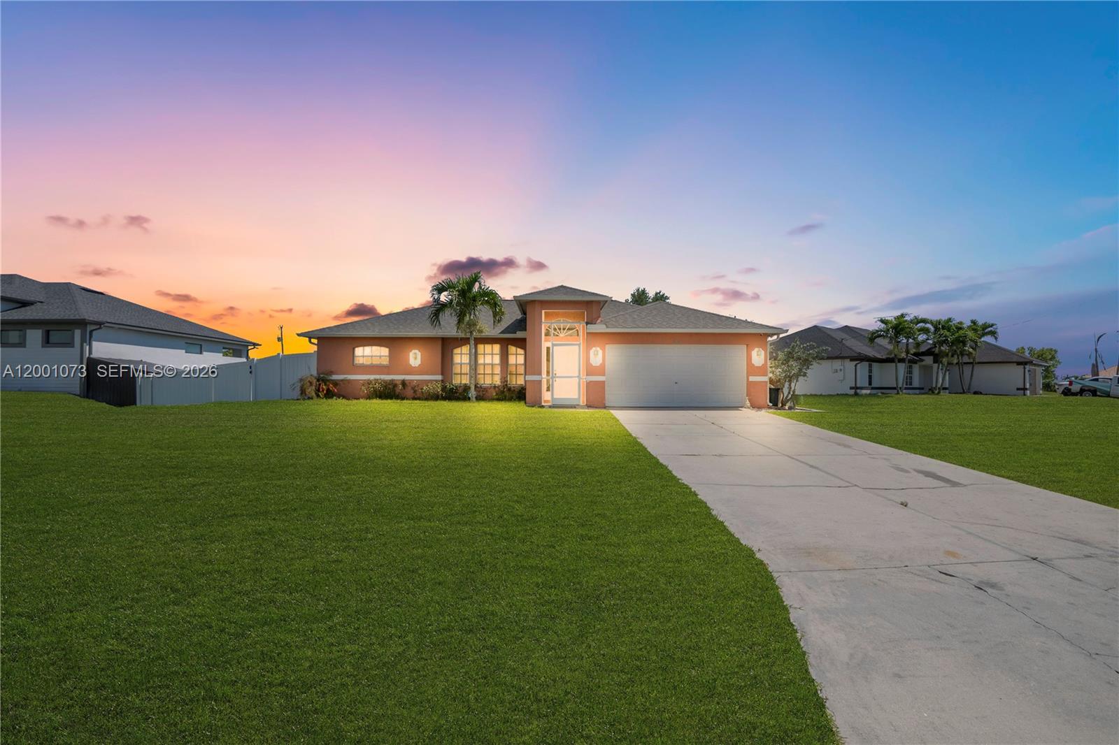 A single-story peach-colored house with a concrete driveway and a large front lawn at sunset — 2840 NW 2ND TERRACE, Cape Coral FL 33993, CAPE CORAL, FL