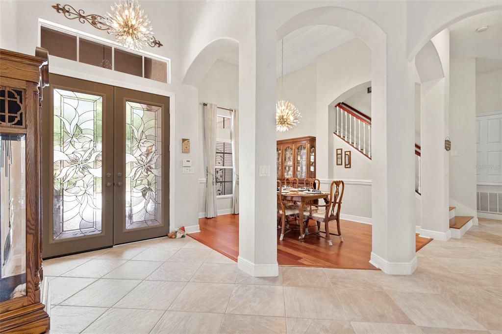 An entryway with tile floors leads to a dining room with hardwood flooring and stairs — 20203 CANE RIVER WAY, TAMPA, FL