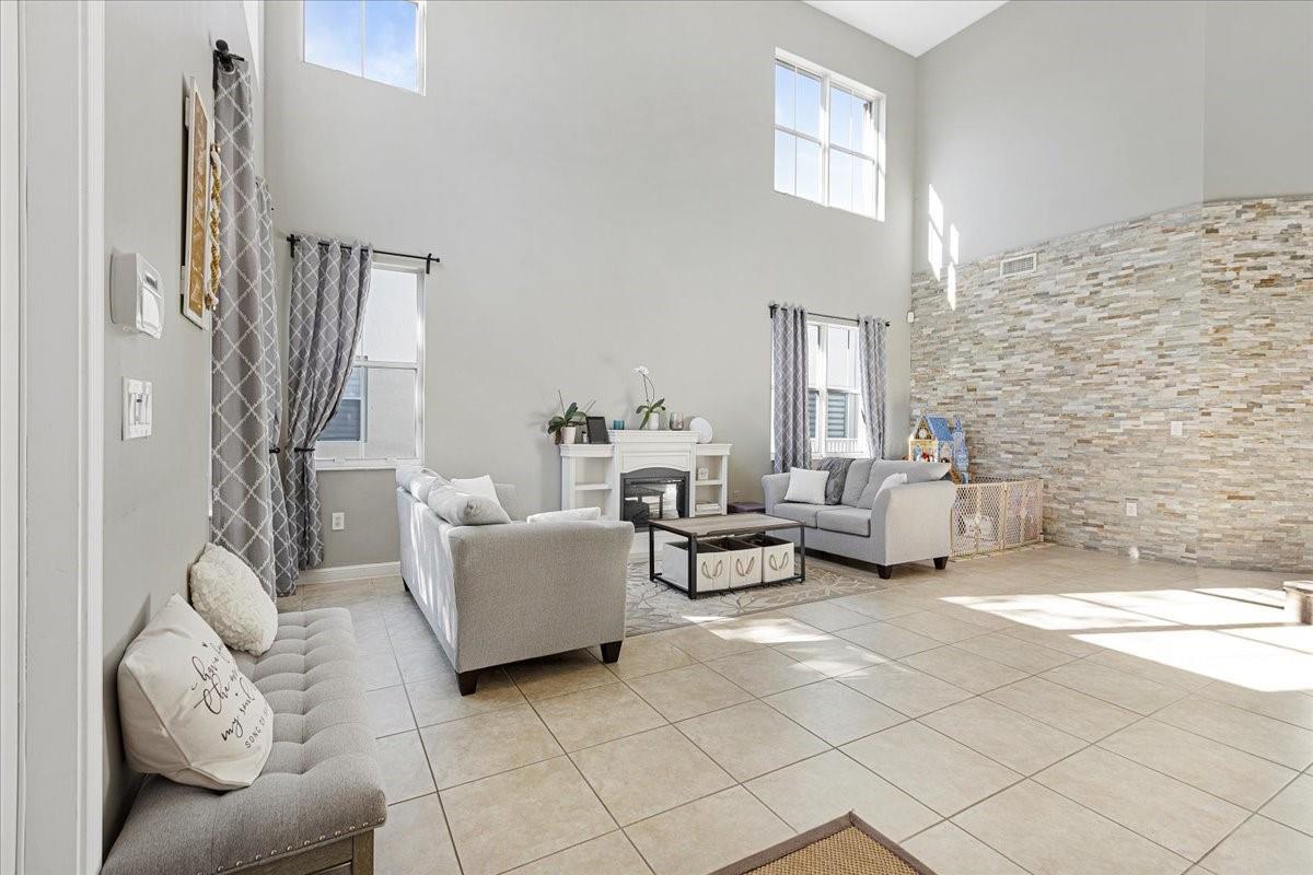 A living room with high ceilings, tile floors, a stone accent wall, and a fireplace — 2316 SW 127th Avenue, Miramar FL 33027, MIRAMAR, FL