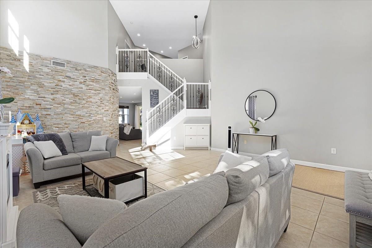 A living room features a stone accent wall, tile flooring, and a staircase with railings — 2316 SW 127th Avenue, Miramar FL 33027, MIRAMAR, FL