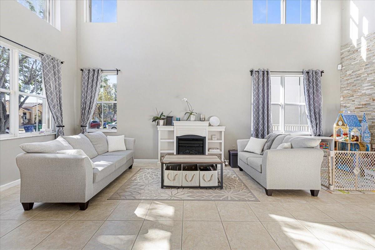 A living room features high ceilings, tile flooring, two gray sofas, and a central fireplace — 2316 SW 127th Avenue, Miramar FL 33027, MIRAMAR, FL